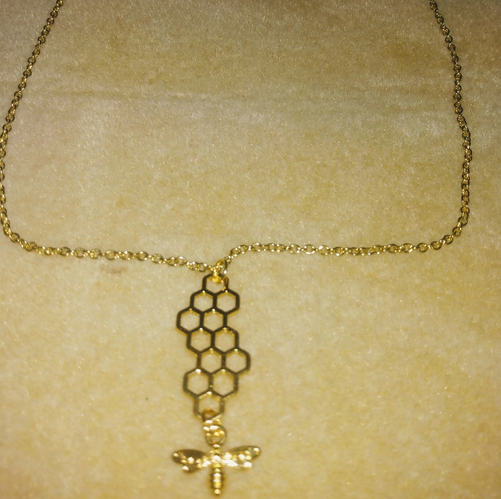 Gold colored necklace withe bee on a honeycomb
